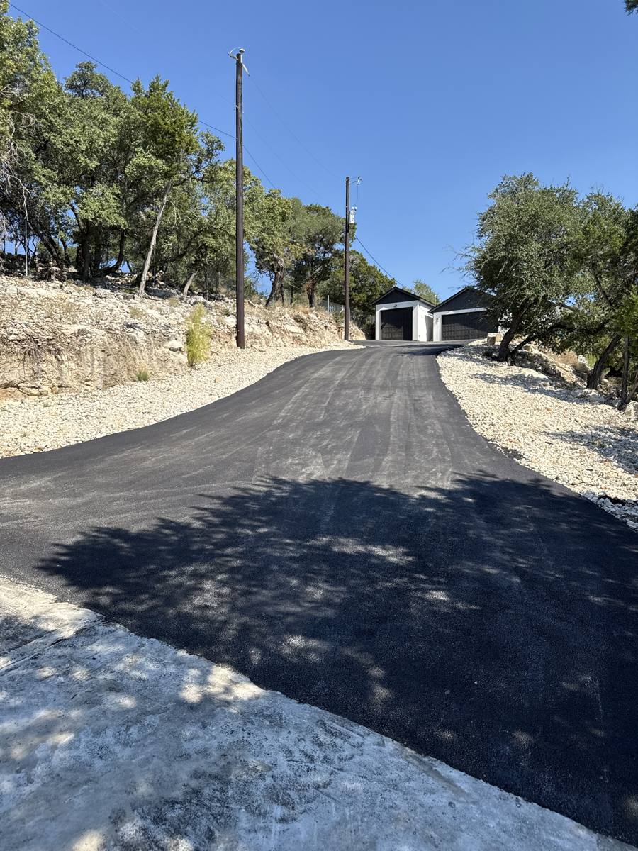 New asphalt driveway up a hillside to a garage